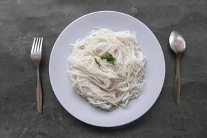 bihun eller vermiceller eller ris spaghetti eller ängel hår eras på tallrik isolerat på svart bakgrund foto