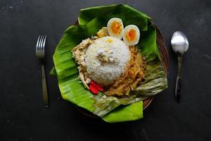 nasi liwet solo- eller sego liwet solo- är en traditionell mat från surakarta. tillverkad från välsmakande ris, chayote och kokt ägg, kyckling, tjock kokos mjölk eras på en banan blad foto