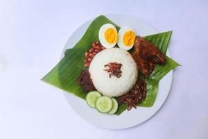 nasi lemak, är traditionell malaysiska tillverkad kokt ägg, bönor, ansjovis, chili sås, gurka. isolerat på vit bakgrund foto