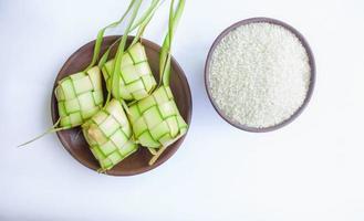 Ketupat i lergods tallrik isolerat på vit bakgrund. Ketupat ,ris klimp är mat eras när idhul Fitri eid mubarak i Indonesien, tillverkad från ris insvept i ung kokos löv, janur foto