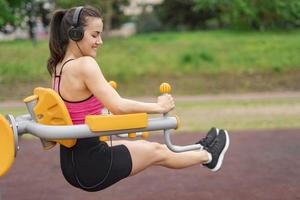 sports arbetssätt ut på de sporter offentlig Utrustning i de utomhus- Gym. en sportigt aktiva kvinna i en parkera foto