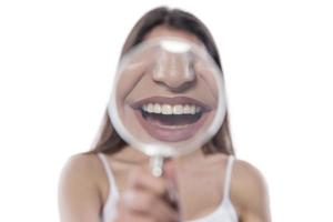 ung kvinna med perfekt leende och friska tänder Bakom förstorande glas foto