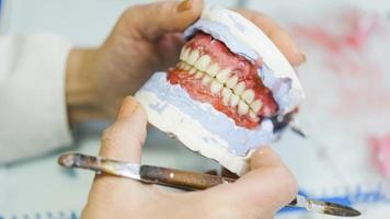 dental protes, proteser, protetik arbete. protetik händer medan arbetssätt på de tandprotes, falsk tänder, en studie och en tabell med dental verktyg foto