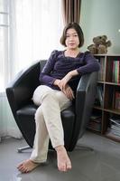 ung asiatisk kvinna kort hår avslappning i levande rum foto