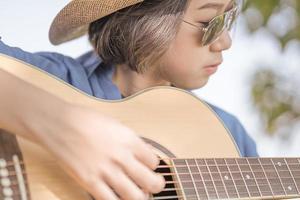 stänga upp kvinna ha på sig hatt och spelar gitarr foto