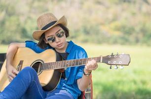 kvinna ha på sig hatt och spelar gitarr på plocka upp lastbil foto