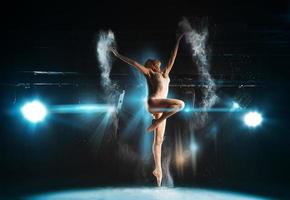 underbar vuxen ballerina Framställ på skede mot spotlights foto