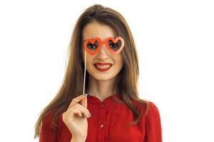 ung charmig underbar flicka skrattar och håller nära öga röd papper glasögon foto