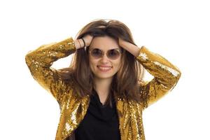 rolig flicka i runda solglasögon bär gyllene jacka och ler foto