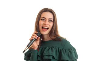 porträtt av en skön ung flicka vem glatt sjunger in i en mikrofon foto
