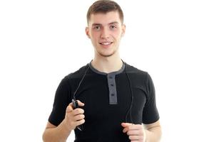 porträtt av en stilig ung kille i en svart t-shirt vem utseende in i de kamera håller de telefon och leende foto