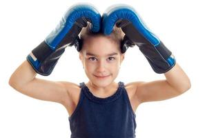 liten flicka innehav händer över de huvud med en stor boxning handskar närbild foto