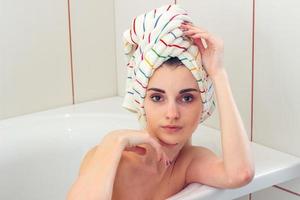 skön ung flicka med handduk på de hår lögner i de badrum och utseende hetero foto