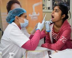 delhi, Indien - november 19, 2022 -stänga upp av kvinna tandläkare håller på med rutin- dental kolla upp till patient, patient liggande på stol på årlig hälsa kolla upp, tandläkare håller på med dental kolla upp till patient foto