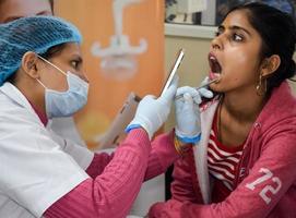 delhi, Indien - november 19, 2022 -stänga upp av kvinna tandläkare håller på med rutin- dental kolla upp till patient, patient liggande på stol på årlig hälsa kolla upp, tandläkare håller på med dental kolla upp till patient foto