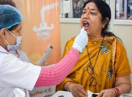 delhi, Indien - november 19, 2022 -stänga upp av kvinna tandläkare håller på med rutin- dental kolla upp till patient, patient liggande på stol på årlig hälsa kolla upp, tandläkare håller på med dental kolla upp till patient foto