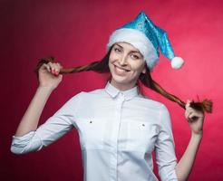 flicka Framställ i de studio på en rosa bakgrund, i en jul hatt foto