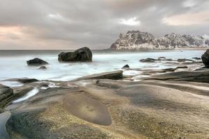 vågor strömmande över utakleiv strand, lofoten öar, Norge i de vinter. foto