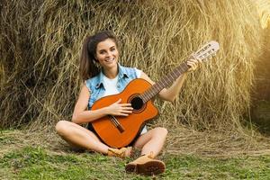 ung och Lycklig kvinna spelar gitarr i de by foto