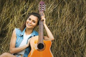 ung och Lycklig kvinna spelar gitarr i de by foto