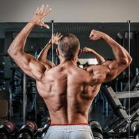 ung man som visar hans muskulös tillbaka i Gym foto