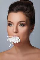 ung kvinna med en full mun av bomull svabbar foto