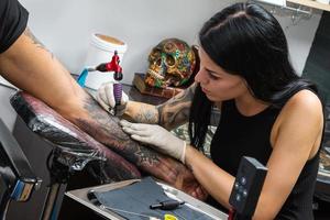 tatuering konstnär under henne arbete foto