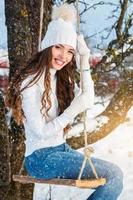 Lycklig flicka på rep gunga på solig vinter- dag foto