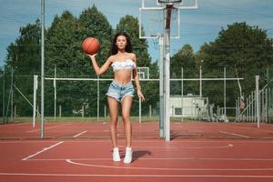 ung sexig kvinna med på en basketboll lekplats foto