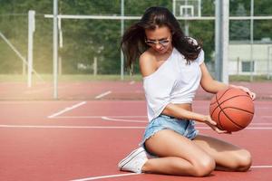 ung sexig kvinna med på en basketboll lekplats foto