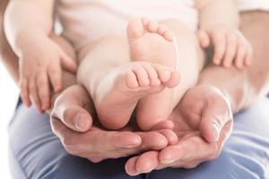 fars händer innehav fötter av hans bebis foto