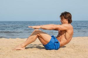 muskulös man under hans träna på de strand foto