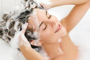 kvinna är tvättning henne hår med schampo foto