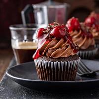 svart skog muffin med vispad ganache och körsbär garnering foto