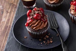 svart skog muffin med vispad ganache och körsbär garnering foto