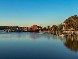 solnedgång längs de mystiker flod i mystiker, connecticut som reflektioner flyta ovan de fortfarande vatten. foto