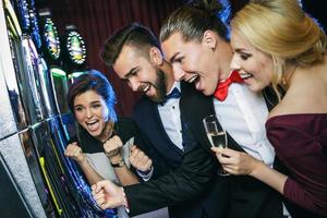 grupp av vänner spelar spår maskiner i kasino foto