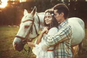 ung Lycklig par och skön vit häst foto