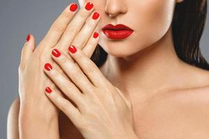 skönhet och kosmetika. kvinna mun och naglar med röd manikyr och läppstift. foto