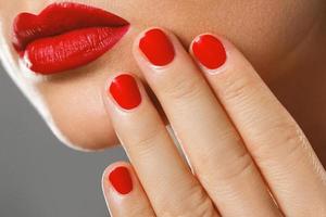 skönhet och kosmetika. kvinna mun och naglar med röd manikyr och läppstift. foto