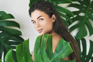 porträtt av ung och skön kvinna med perfekt slät hud i tropisk löv foto