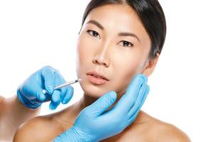 asiatisk kvinna under mun förstärkning procedur på vit bakgrund foto