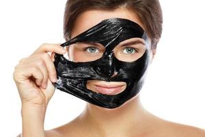 skön kvinna är avlägsnande renande mask från henne ansikte foto