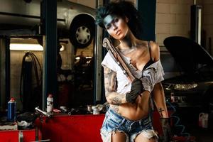 kvinna mekaniker i de garage med konstnärlig smink på henne ansikte stiliserade tycka om en smutsig fläck foto