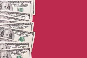 papper pengar, bakgrund av ett hundra dollar räkningar på en karmin röd bakgrund. kopia Plats. foto