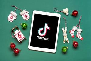 Bangkok, thailand. december 2022 smartphone tik tok Ansökan ikon, logotyp på skärm, trådlös hörlurar på grön bakgrund trendig social media nätverk begrepp platt lägga topp se ny år, jul foto