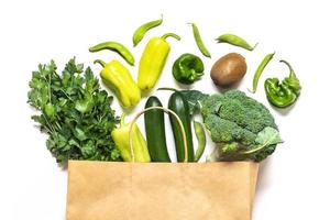 eco vänlig papper affär väska med rå organisk grön grönsaker isolerat på vit bakgrund platt lägga, topp se noll avfall, plast fri begrepp friska rena äter diet och detox, lantbruk begrepp foto