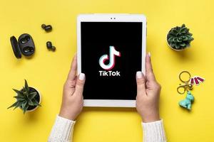 Bangkok, thailand. oktober 2022 läsplatta tik tok Ansökan ikon, logotyp på skärm och trådlös hörlurar på färgrik bakgrund trendig social media nätverk begrepp platt lägga topp se foto