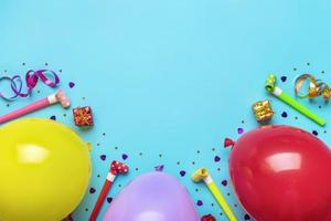 färgrik fest ram med röd gåva låda med olika fest konfetti, ballonger, streamers, poker och dekorationer på blå bakgrund. Semester kort platt lägga topp se Lycklig födelsedag fest begrepp foto