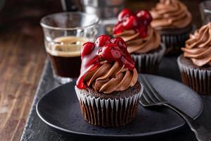 svart skog muffin med vispad ganache och körsbär garnering foto